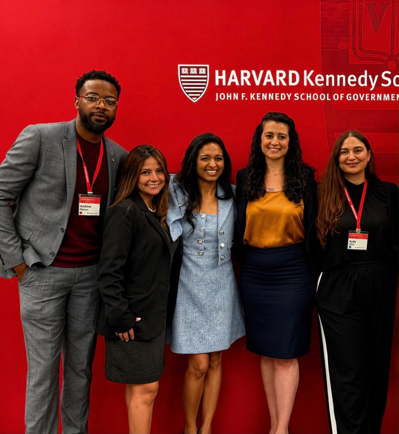 Andrew with classmates in front of the Harvard Kennedy School wall