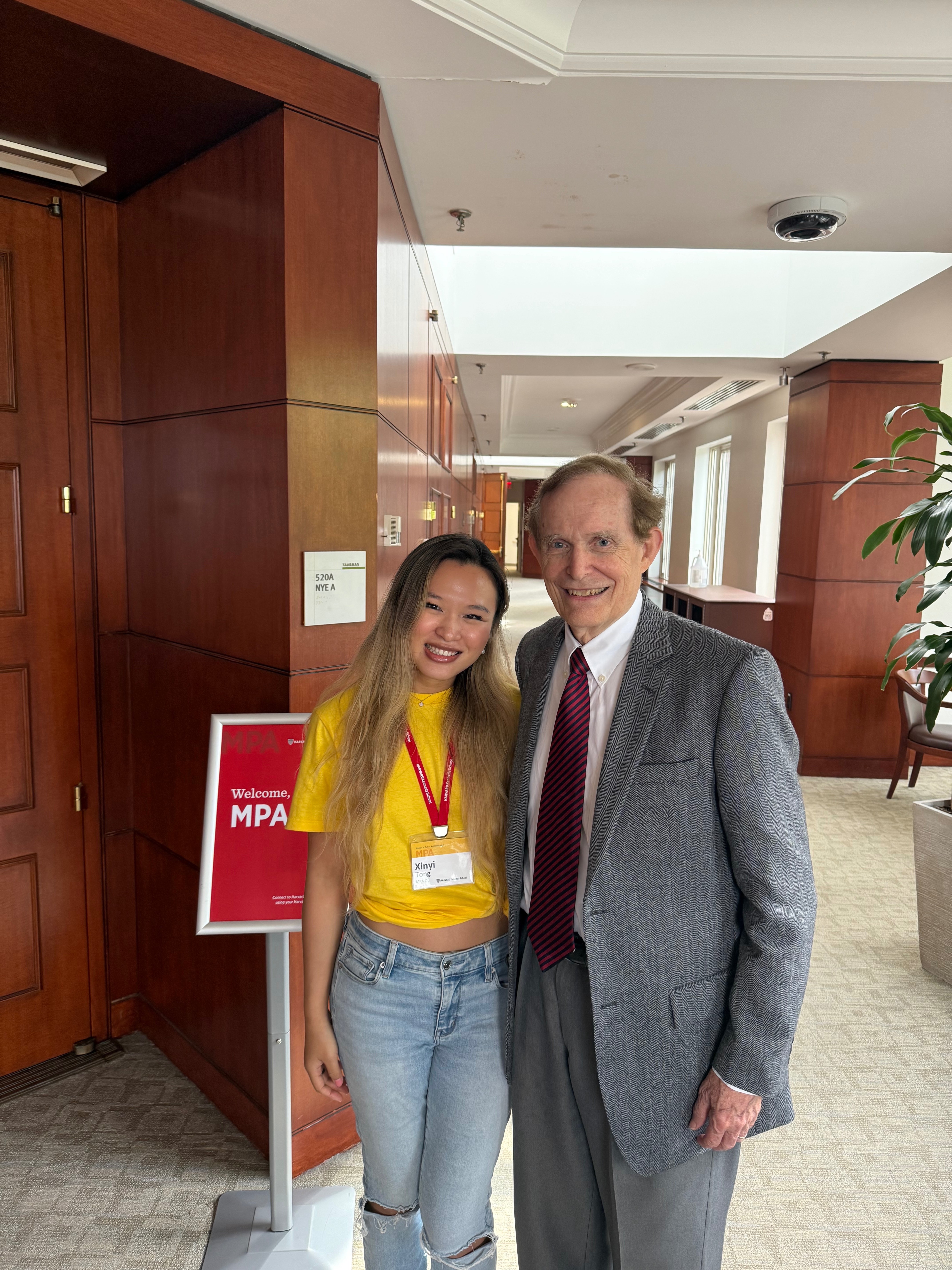 Xinyi welcoming the MPA cohort alongside Professor Roger Porter in the Taubman hallway