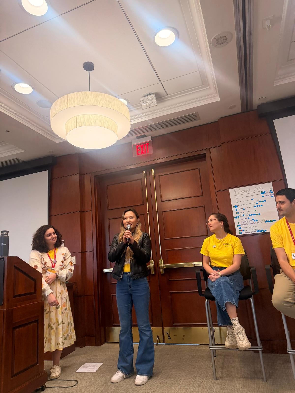 Xinyi speaking on the microphone during an orientation session with the OL team