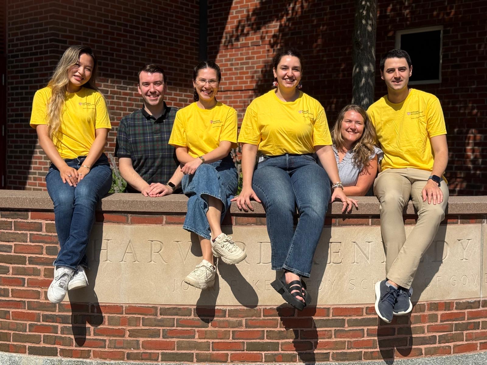 Xinyi with fellow Orientation Leaders in yellow HKS tees on the Harvard Kennedy School wall